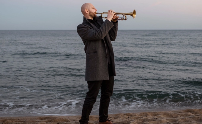 man playing trumpet by seaside