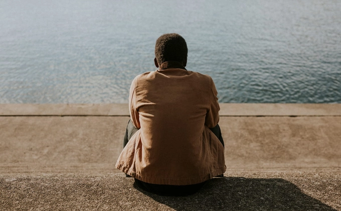 man sitting by water
