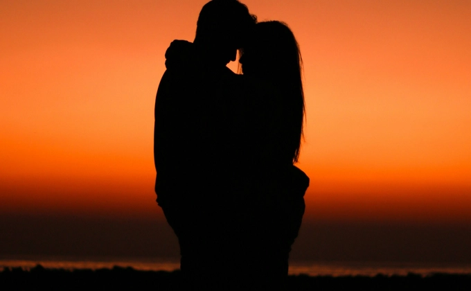 A Silhouette of two lovers hugging at sunset