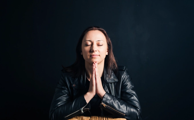 A woman praying fervently with a solemn face