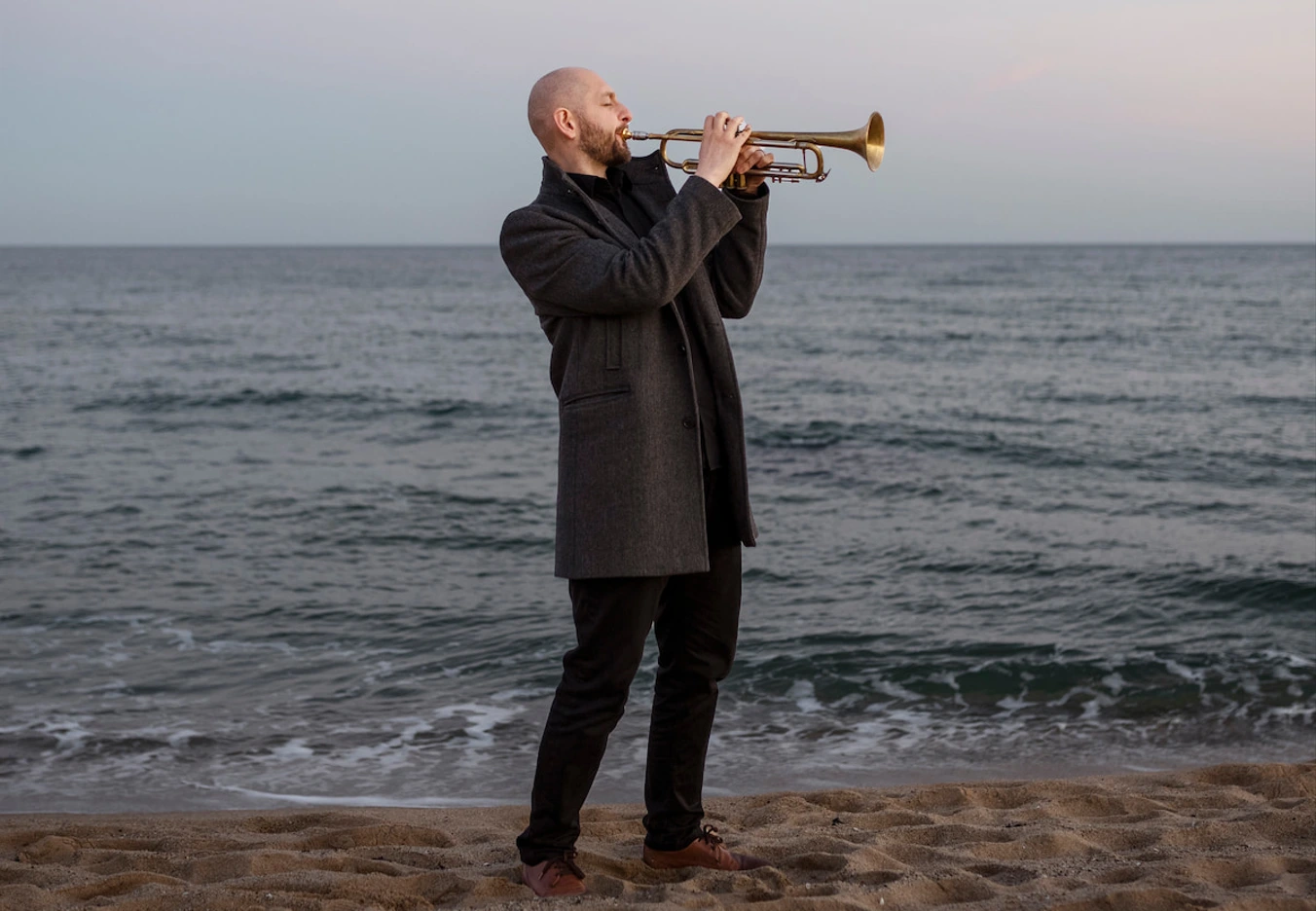 man playing trumpet by seaside