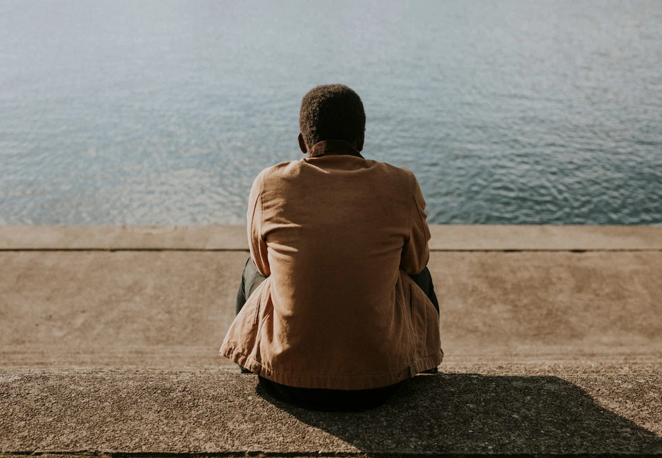 man sitting by water